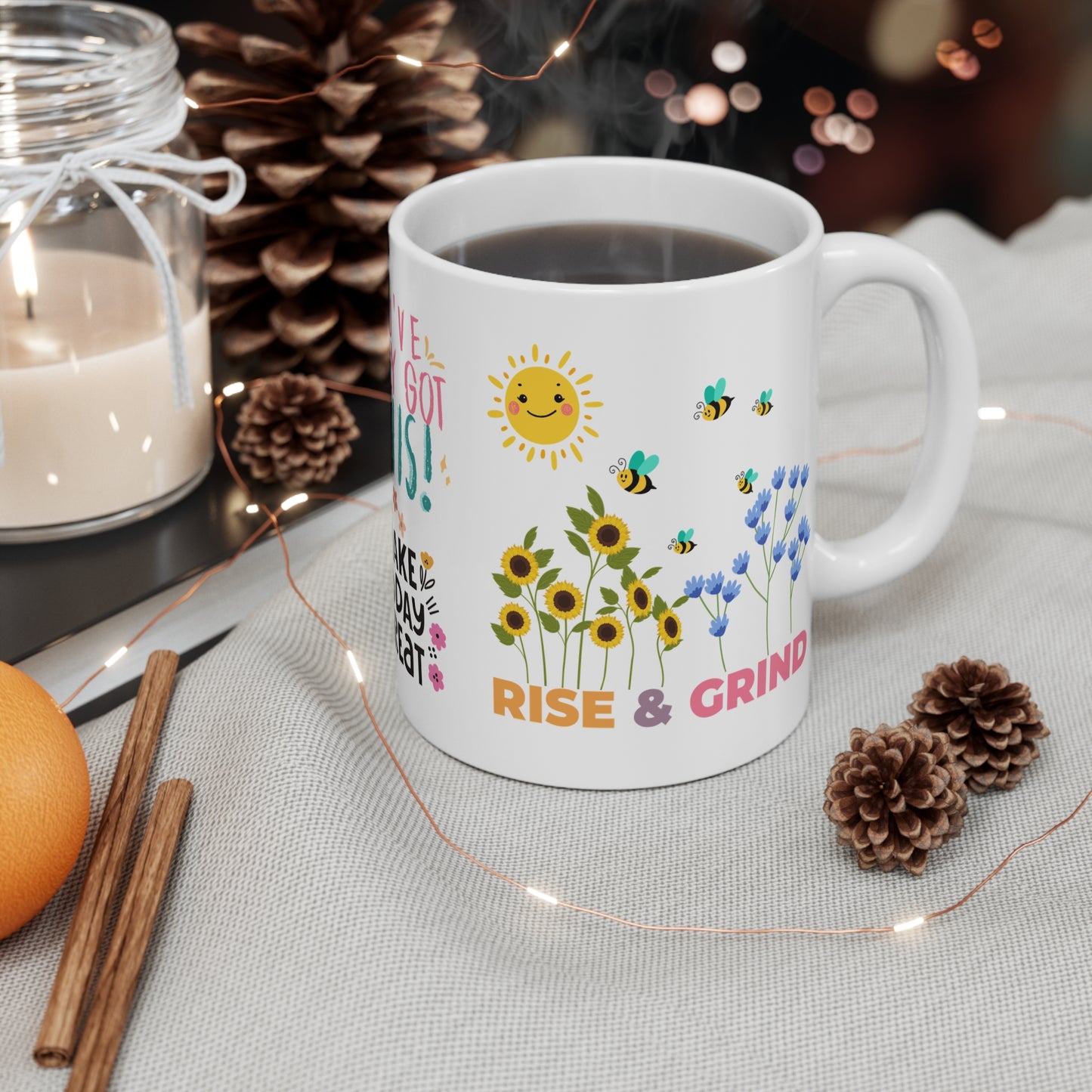 11 oz white ceramic mug with 'Rise & Grind' in bold colorful letters and a graphic of smiling sun, colorful flowers and bees, uplifting and motivational design