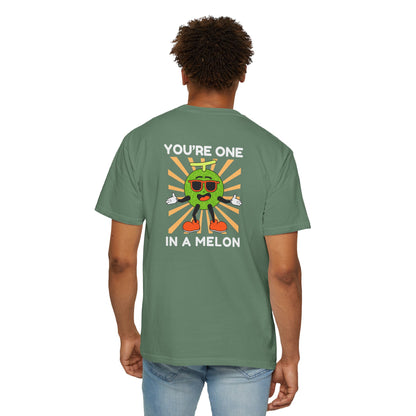 Man wearing a light green unisex t-shirt with a large back design featuring 'You're One in a Melon' text and a smiling melon wearing sunglasses on a retro background, uplifting and fun graphic tee