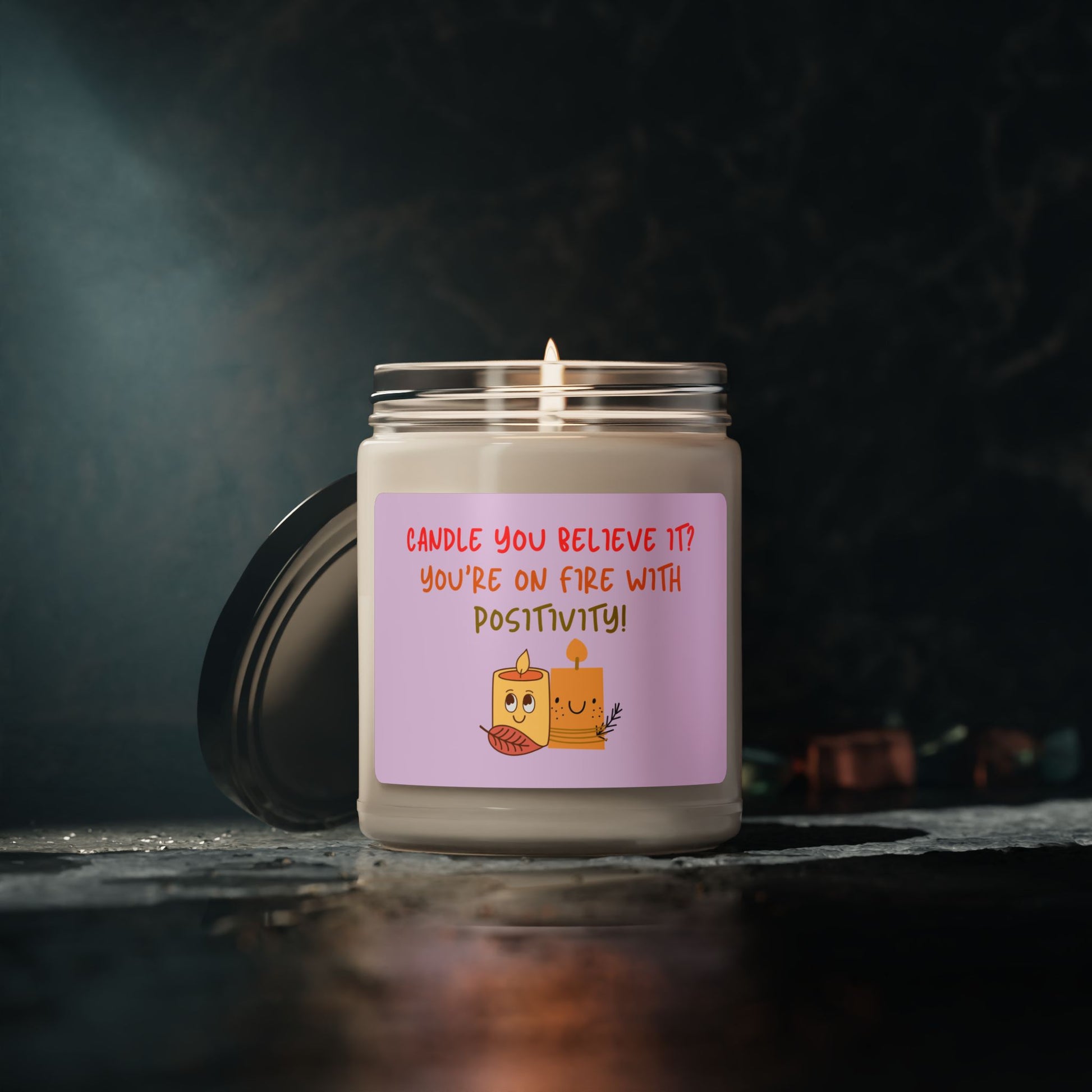 A soy candle in a 9oz in a glass jar with a phrase 'Candle You Believe It' on the label, featuring graphic of two smiling candles