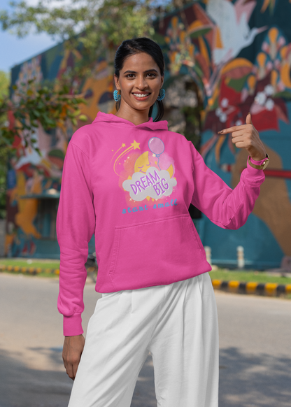 a woman wearing a pink unisex hoodie withe text 'dream big, start small', featuring a smiling moon behind a cloud