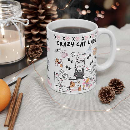 An 11oz ceramic coffee mug with text 'Crazy cat Lady' in bold lettering, featuring cute cat graphics on a table